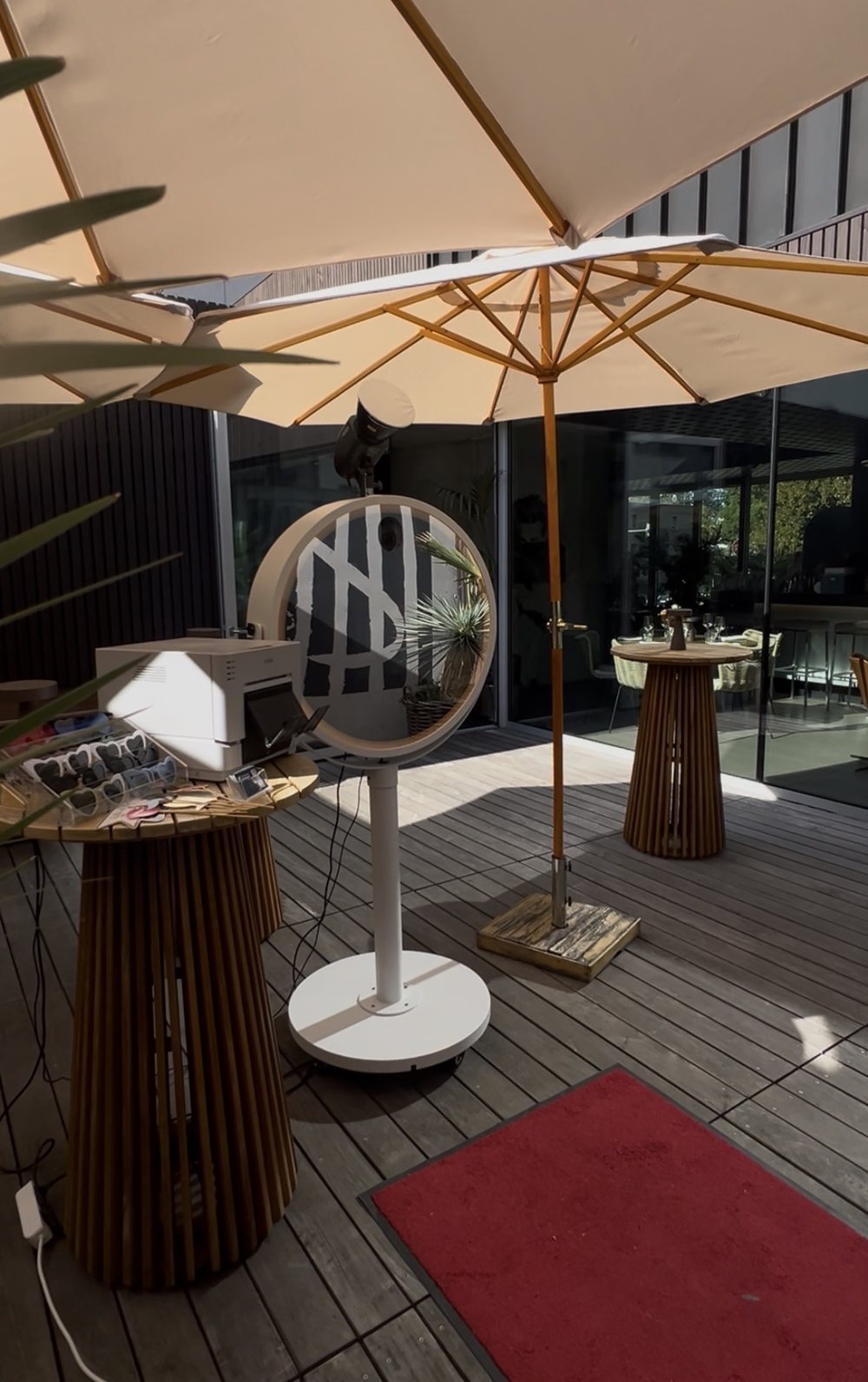 Beauty Mirror mit Drucker und Requisiten auf einer Terrasse unter Sonnenschirmen